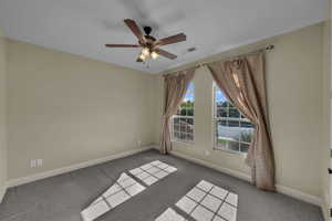 Empty room featuring a ceiling fan and carpet floors