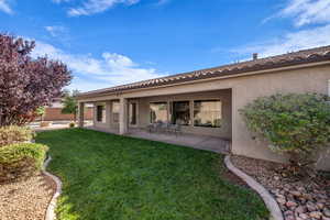 Rear view of property featuring a patio, stucco siding, and a tile roof
