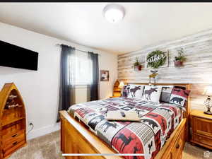 Bedroom with wood walls, an accent wall, and light carpet