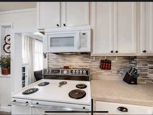Kitchen featuring white appliances, white cabinetry, and tasteful backsplash