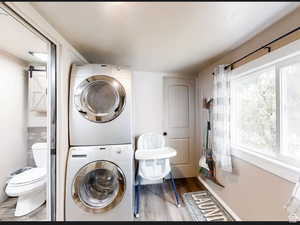 Bathroom with stacked washing machine and dryer and wood finished floors