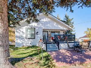 View of front facade featuring a patio area, a front lawn, and board and batten siding