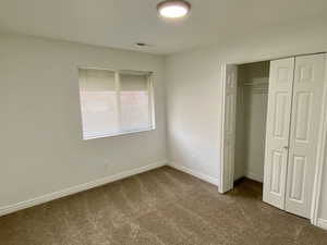 Unfurnished bedroom with a closet and dark colored carpet