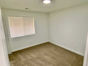 Empty room featuring carpet flooring and baseboards