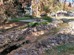 View of property's community with a patio, a water view, and a lawn