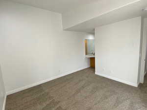 Empty room featuring dark colored carpet and baseboards