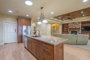 Kitchen featuring built in shelves, hanging light fixtures, brown cabinets, open floor plan, and light wood finished floors