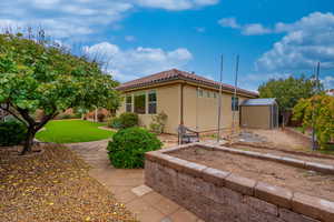 View of side of home with a storage unit, stucco siding, and a tile roof