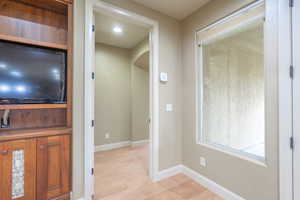 Corridor with baseboards and light wood-style flooring