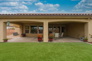 Back of property featuring a tiled roof, stucco siding, and a patio area