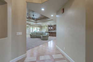Corridor featuring a raised ceiling, recessed lighting, light carpet, a chandelier, and a textured ceiling