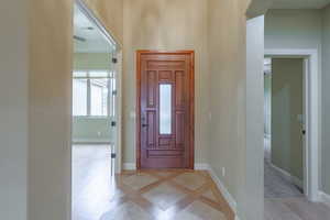 Foyer featuring inlaid floor details and baseboards