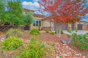 View of front of property with stone siding, stucco siding, driveway, and a tile roof