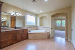 Bathroom with vanity, a bath, light wood finished floors, and recessed lighting