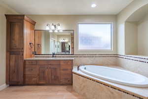 Bathroom with vanity, a garden tub, and recessed lighting