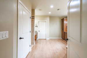 Hall with light wood finished floors and recessed lighting