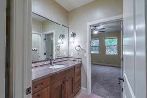 Bathroom featuring vanity, ceiling fan, and light carpet