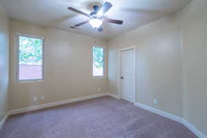 Carpeted spare room featuring baseboards and a ceiling fan