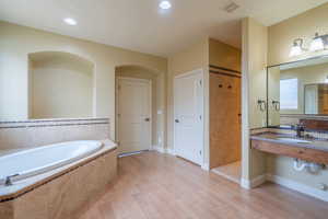 Full bath featuring vanity, a bath, light wood finished floors, a tile shower, and recessed lighting