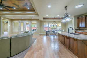 Living room with healthy amount of natural light, a raised ceiling, light wood-type flooring, recessed lighting, and a chandelier