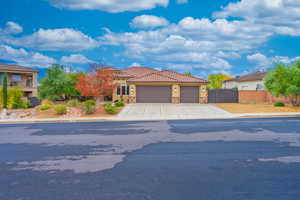 Mediterranean / spanish home with stone siding, an attached garage, a gate, concrete driveway, and stucco siding