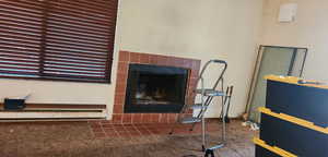 Living area featuring a tiled fireplace, baseboard heating, and carpet flooring