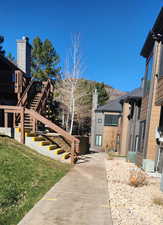 View of property exterior featuring stairway, a chimney, a yard, and a deck