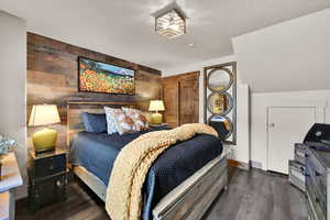 Bedroom featuring wood walls, an accent wall, a closet, dark wood-type flooring, and recessed lighting