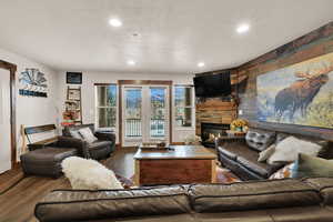 Living room with a fireplace, wood finished floors, recessed lighting, and an accent wall