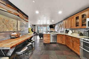 Kitchen with recessed lighting, open floor plan, a peninsula, glass insert cabinets, and stainless steel appliances