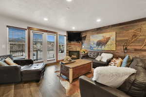 Living area with wooden walls, a fireplace, hardwood / wood-style floors, an accent wall, and recessed lighting