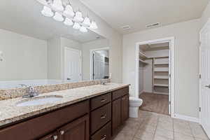 Bathroom featuring huge double vanity with granite countertops, separate tub and shower  and a spacious walk in closet