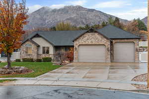 View of front of property with a front lawn, a shingled roof, concrete driveway, a garage, and a mountain view