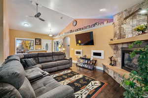 Living room with vaulted ceiling, dark wood-type flooring, a ceiling fan, and a fireplace