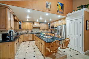 Kitchen featuring glass insert cabinets, recessed lighting, stainless steel appliances, a center island, and backsplash