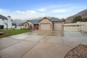 Ranch-style home with a mountain view, concrete driveway, a garage, roof with shingles, and a gate