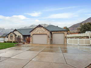 Ranch-style home with a mountain view, concrete driveway, a garage, roof with shingles, and a gate