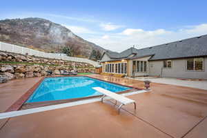 View of swimming pool with a fenced backyard, a diving board, a patio area, a mountain view, and a sunroom