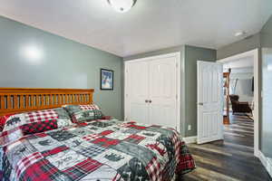 Bedroom featuring a textured ceiling, dark wood-style flooring, and a closet