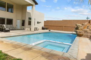 View of pool with a patio area, a fenced backyard, a pool with connected hot tub, and an outdoor hangout area