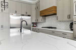 Kitchen featuring light stone countertops, gray cabinets, and appliances with stainless steel finishes