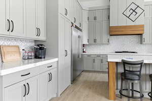 Kitchen with gray cabinets, a breakfast bar, and backsplash