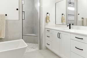 Bathroom featuring vanity, a freestanding tub, a shower stall, and light tile patterned floors