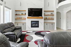 Living area featuring a high end fireplace, light wood finished floors, and arched walkways