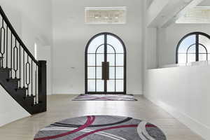Entryway with stairway, arched walkways, a high ceiling, french doors, and wood tiled floors