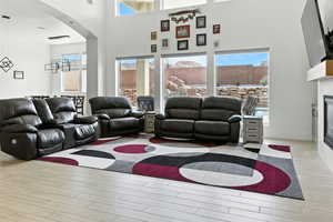Living area featuring a glass covered fireplace, wood tiled floors, arched walkways, and a towering ceiling