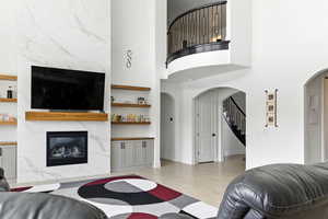 Living area featuring a premium fireplace, stairs, light wood finished floors, and a high ceiling