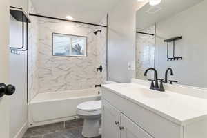 Bathroom featuring vanity, shower / bathtub combination, and dark tile patterned floors