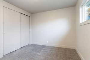Unfurnished bedroom with light carpet and a closet