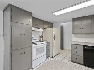 Kitchen featuring gray cabinetry, white appliances, light countertops, and under cabinet range hood